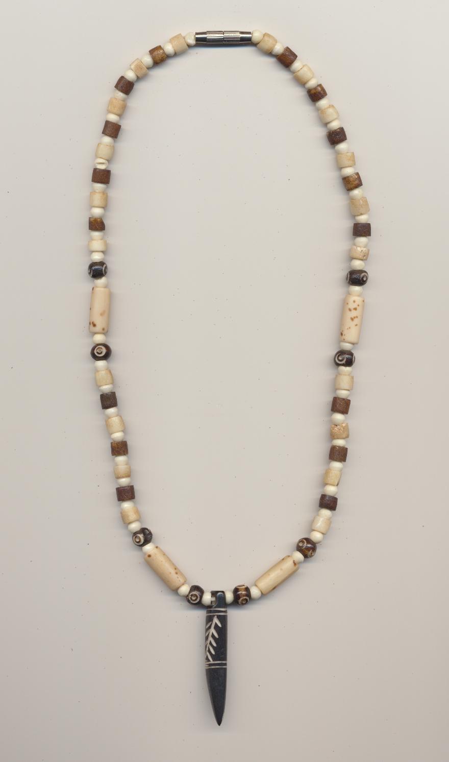 Necklace for boys made of bleached, dyed and with eye motif carved bone beads, with carved decorated bone animal toothlike pendant, India, 1990's, length necklace 19'' 48cm., pendant 2'' 4.5cm.
